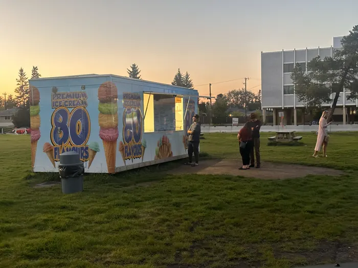 An 80 Flavours trailer glowing at golden hour with customers at the window