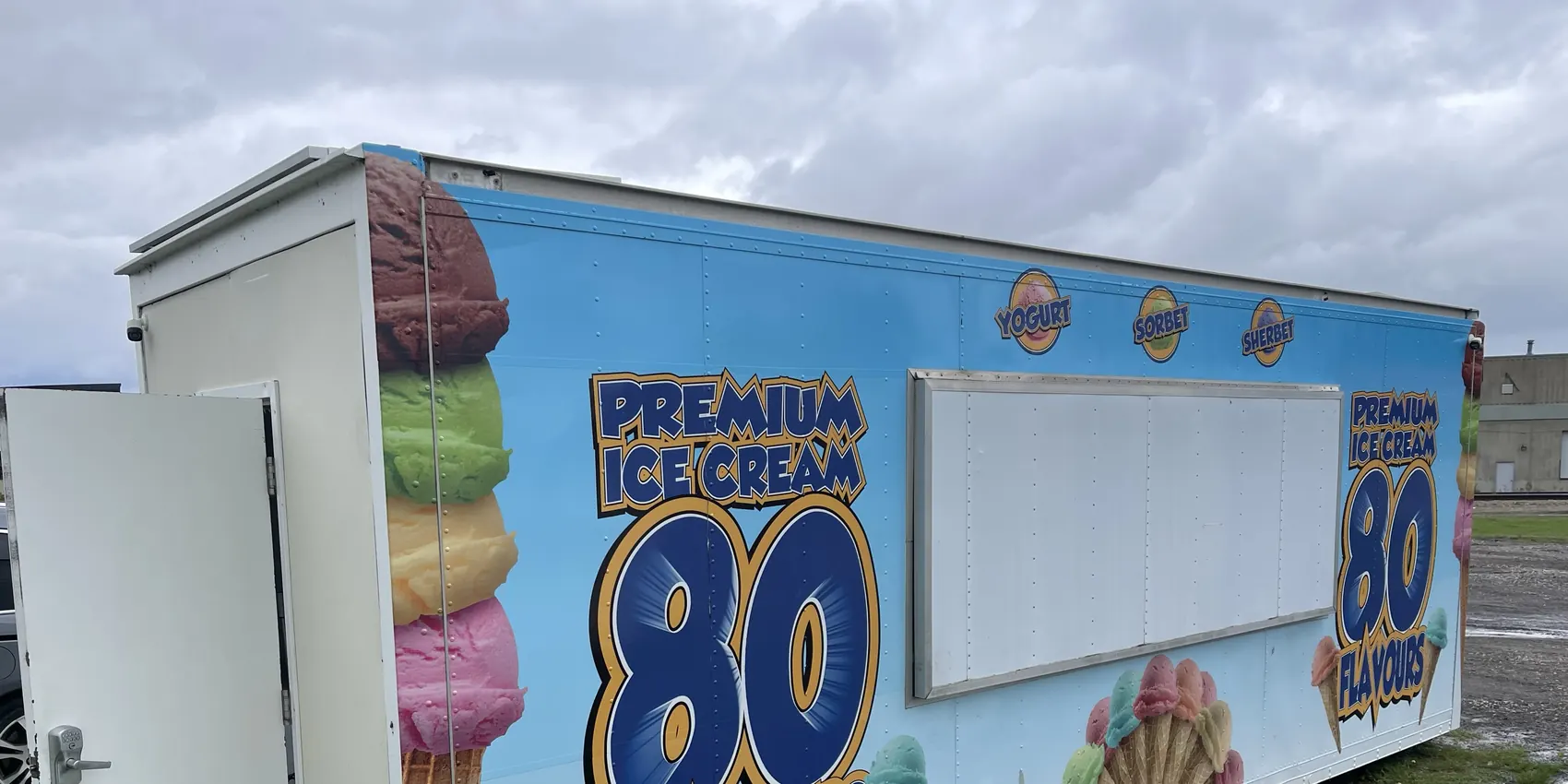 The side of an 80 Flavours 24-foot trailer in its full wrap, parked in daylight